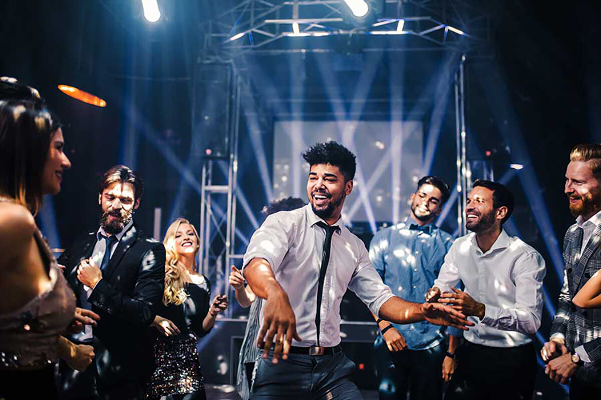 Guests dancing and celebrating in front of stage lighting at a corporate party event