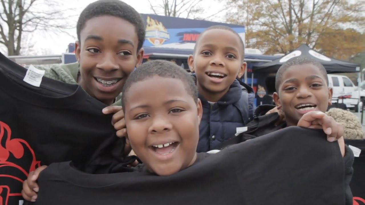 Four young boys holding up T-shirts at an NBA events.