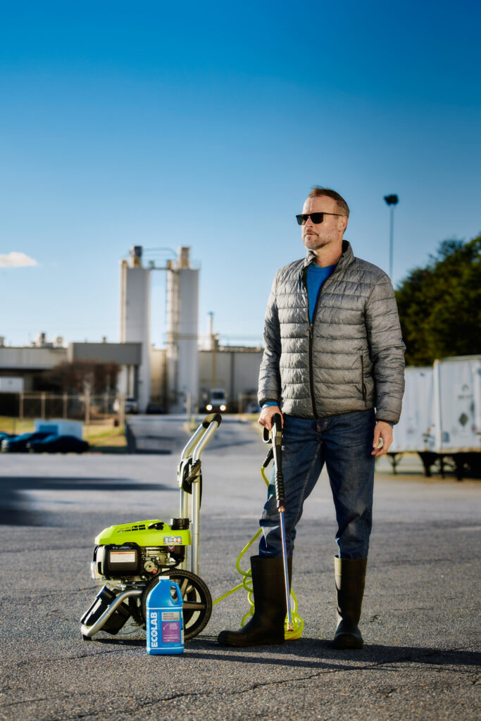 A man standing beside an ecolab power washer.