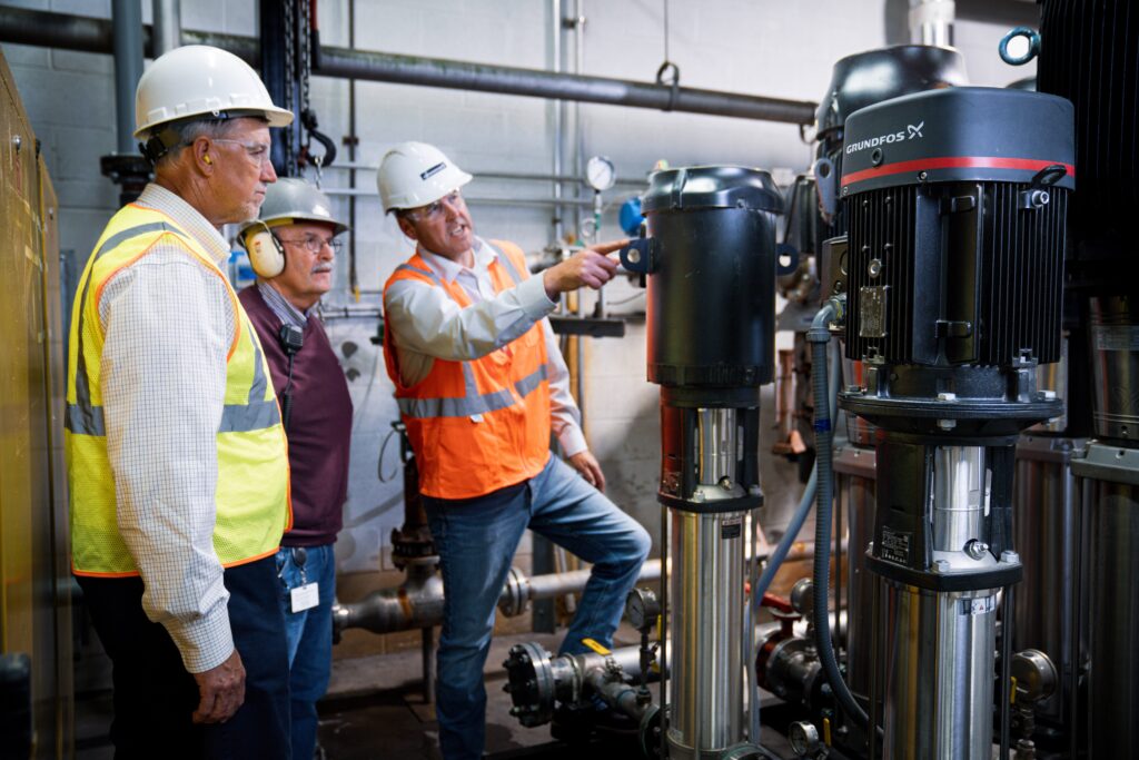 Three men looking at a water pump product.