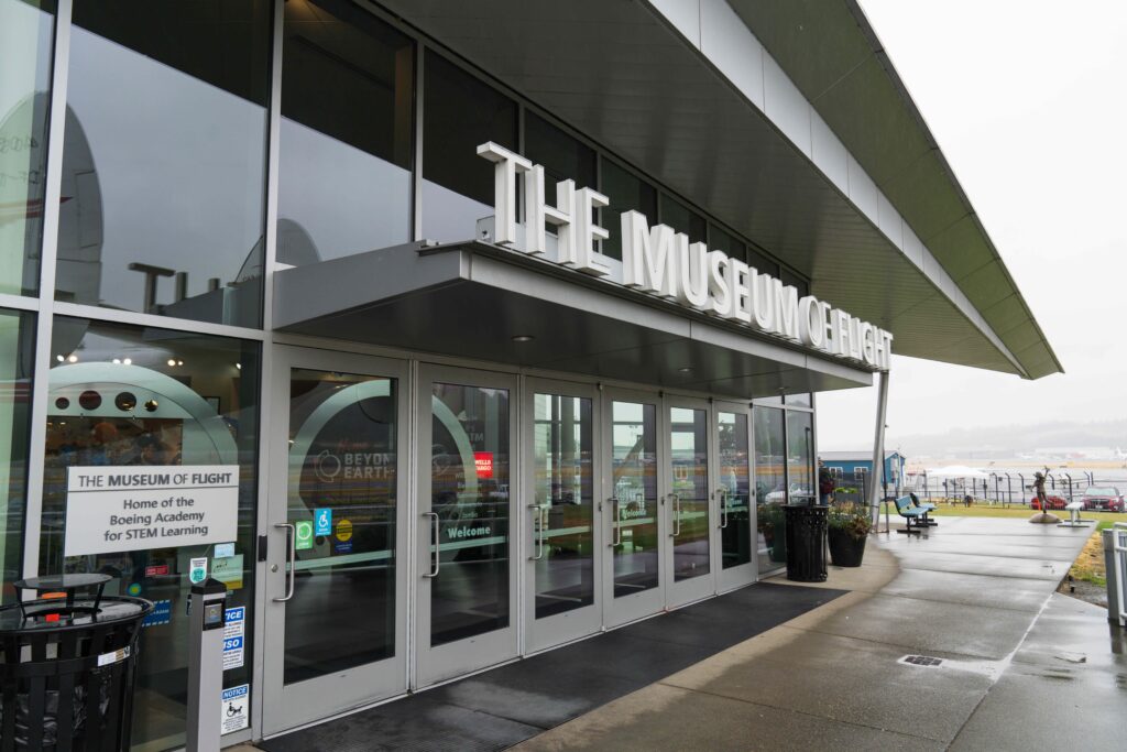 Entrance to The Museum of Flight with doors and sign.