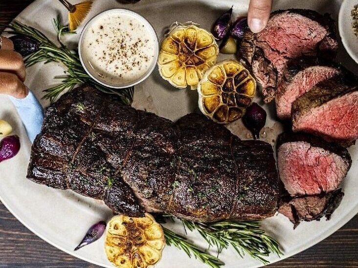 Overhead view of roasted beef platter with garlic and rosemary for food photography production