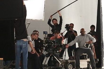 Film crew shooting a commercial video production in studio with boom mic and camera equipment