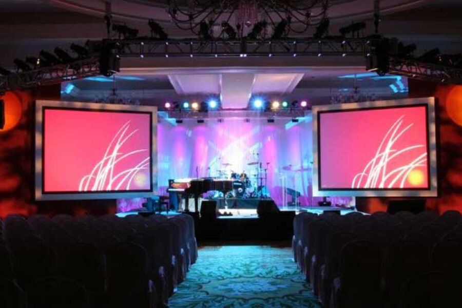 Corporate event ballroom with dual LED screens and stage lighting setup