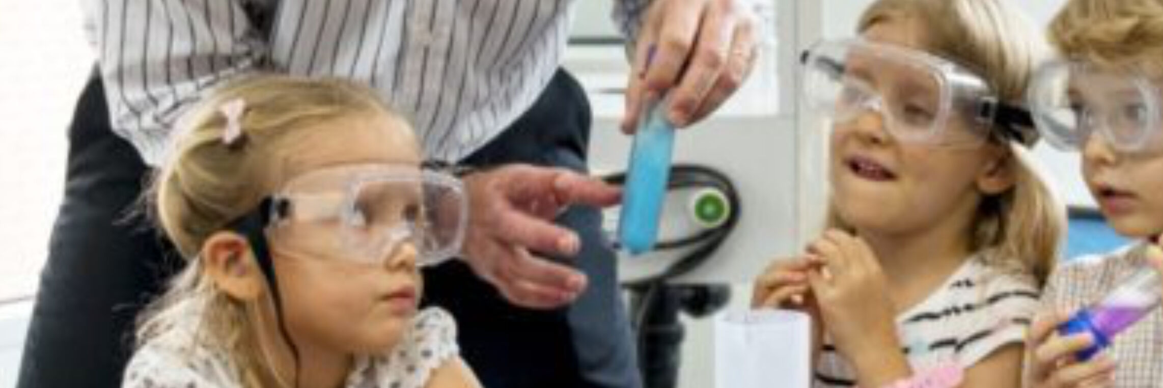 Children in safety goggles watching science experiment, education video production for Discovery