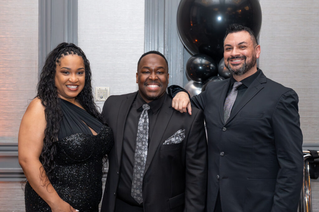 Three attendees in formal attire posing together at the SOAR Hawthorne Leadership Conference gala