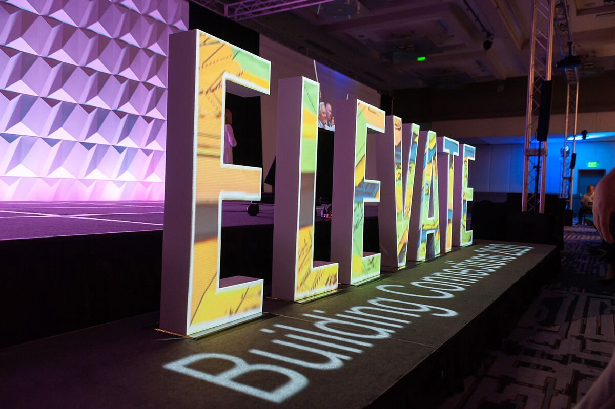 Illuminated ELEVATE Building Connections marquee letters on a stage runway, K2 Productions event production