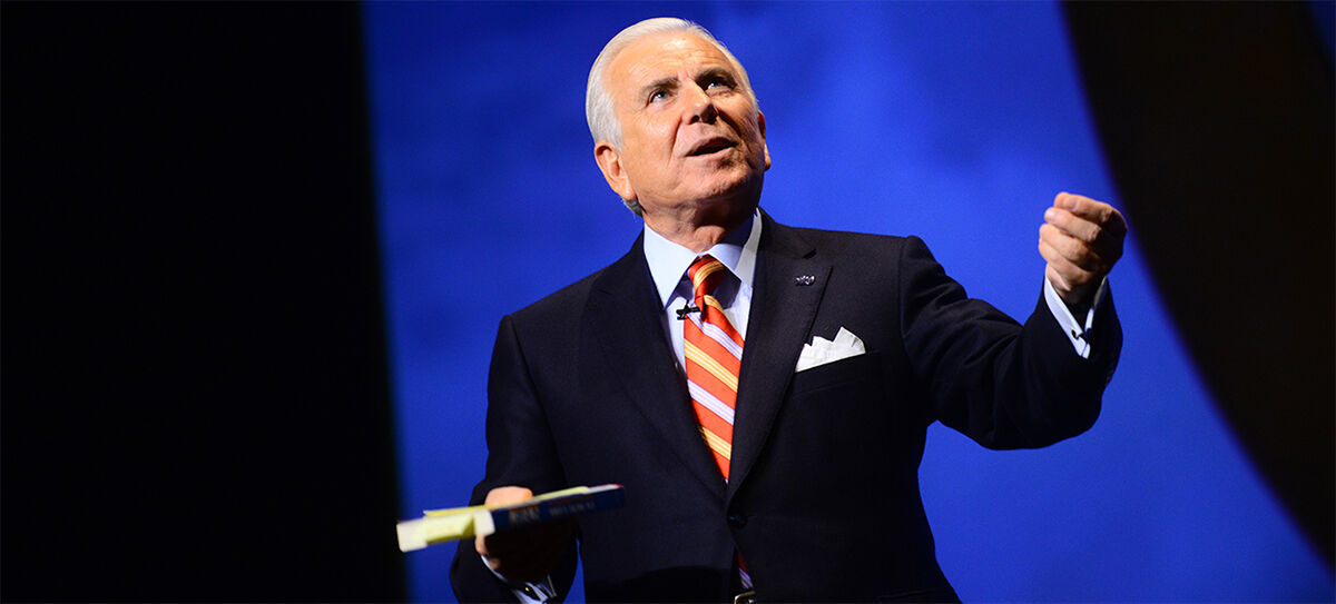 Keynote speaker gesturing emphatically on stage during a corporate conference, K2 Productions event videography